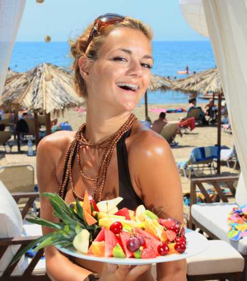A picture of a girl with a dish of fruits.