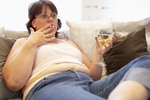Obese people habits: a woman smoking, drinking and watching tv