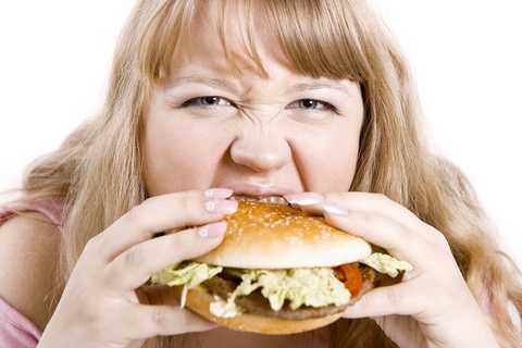 A fat girl devouring a hamburger